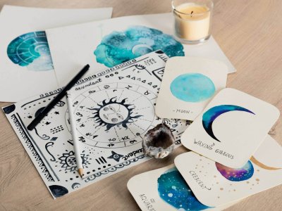 selective-focus-of-birth-chart-and-cards-with-watercolor-drawings-of-moon-phases-and-candle-on-table.jpg